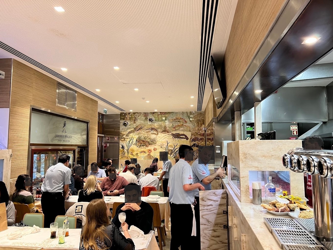 Restaurant interior in Lisbon. DIG-IN marks seven brands (Johnnie Walker, Sagres, Sagres Bohemia, Absolut, Lipton Ice Tea, Paladin, Hellmann’s) and operational signals: TV, POS, open kitchen, tiled mural and 16 tables of two.